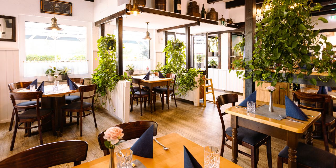 Schöner Restaurantinnenraum mit Holztischen und grünen Zimmerpflanzen